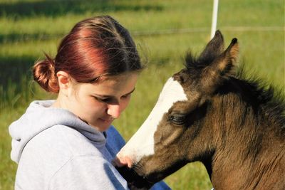 Teenager cuddling with a two weeks old foal