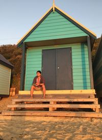 Portrait of man sitting on house against building