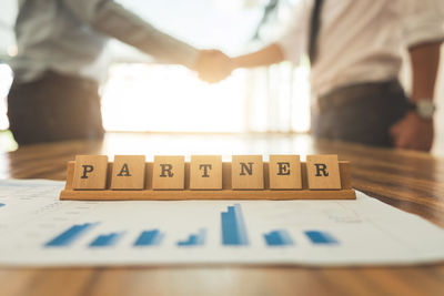 Businessmen shaking hands with graph and text at desk in office