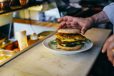 Midsection of man preparing burger in restaurant