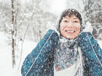 Smiling woman is playing with knitted hat. fun in snowy winter forest. woman laughs.