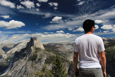 Man standing on landscape against cloudy sky