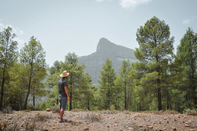 Full length of man standing amidst trees in forest against sky