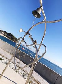 Ferris wheel by sea against clear blue sky