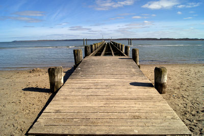 Wooden pier on sea against sky