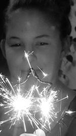 Close-up portrait of young woman with fire crackers at night