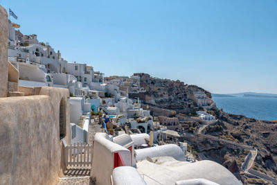 Buildings by sea against clear blue sky