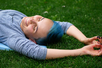 Happy young woman sleeping on grassy field