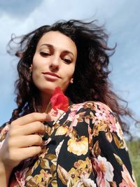 Portrait of young woman looking at camera holding a poppy flower in her hand