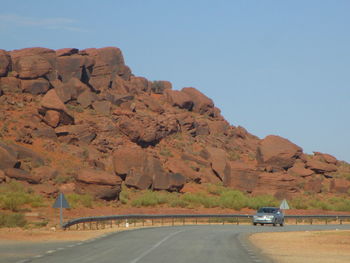 Car on road by mountains against clear sky