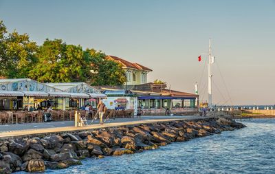 Buildings by sea against clear sky