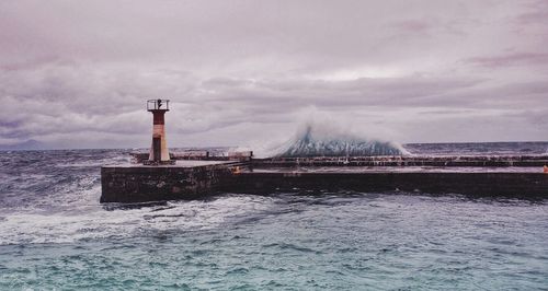 Lighthouse by sea against sky