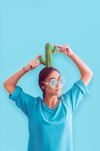 Young woman with cactus against blue background