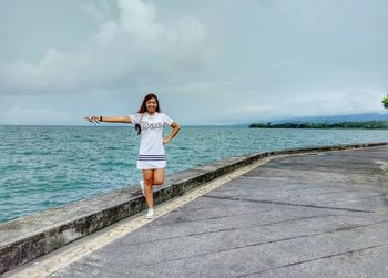 Full length of woman standing by sea against sky