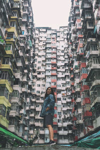 Portrait of smiling woman standing against building in city