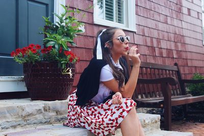 Young woman wearing sunglasses while sitting outdoors