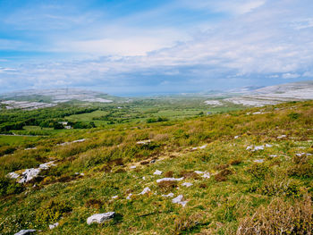 Scenic view of green landscape against cloudy sky