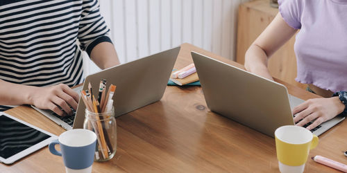 Midsection of woman holding coffee cup on table