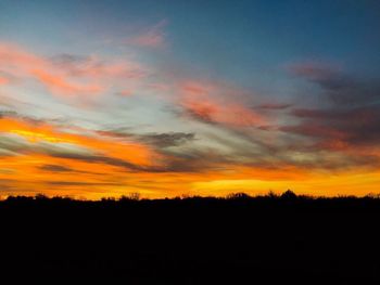 Silhouette landscape against dramatic sky during sunset