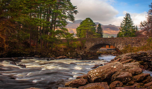 Arch bridge over river against sky