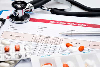 Pills and stethoscope with medication plan at table