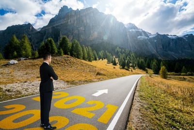 Rear view of man on road against mountain range