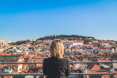 Rear view of woman standing against cityscape