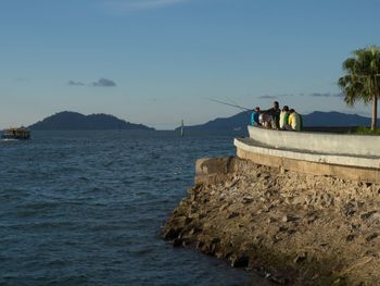 People on boat in sea against sky