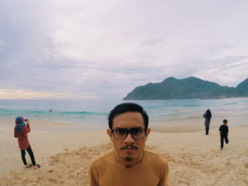 Friends standing on beach against sky