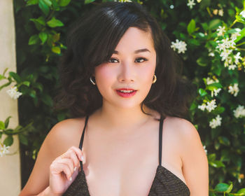 Portrait of young woman standing against plants