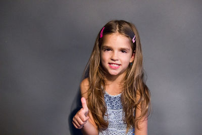 Portrait of smiling girl standing against wall