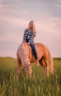 Portrait of teenage girl riding horse on land against sky