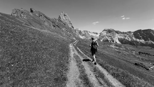 Rear view of man walking on mountain against sky