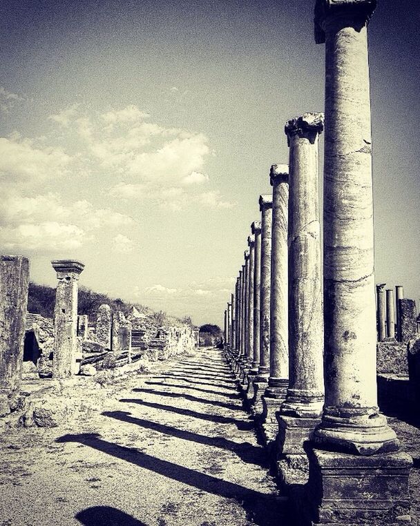 shadow, in a row, sunlight, sky, architectural column, architecture, the way forward, day, column, pole, cloud, outdoors, repetition, tall - high, diminishing perspective, pathway, surface level, tranquil scene, tall, tranquility, long, solitude, vanishing point, memories