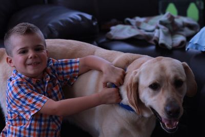 Portrait of cute boy holding dog at home