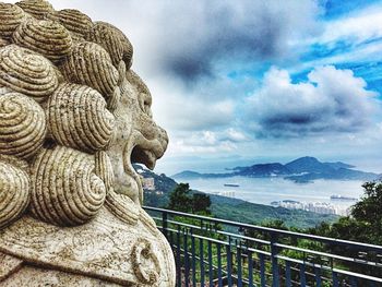 Statue by sea against cloudy sky