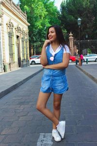 Portrait of young woman standing on street in city