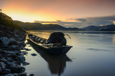 Boat moored in lake at sunset