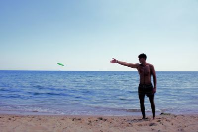 Rear view of man standing at beach against sky