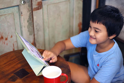 Boy looking up while sitting on paper