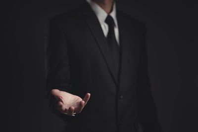 Midsection of man standing against black background