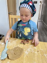 A young boy making gingerbread men in kitchen at home