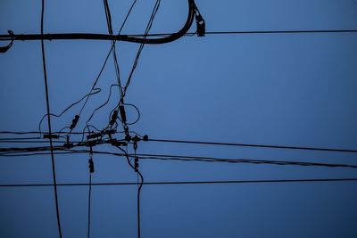 Low angle view of electricity pylon against clear blue sky