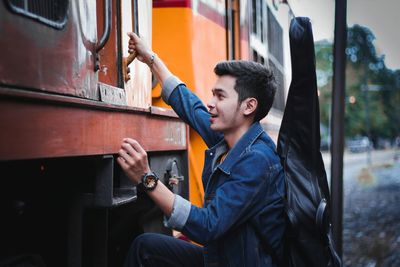 Side view of young man holding train