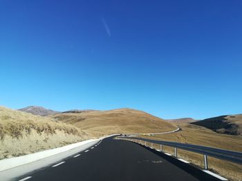 Road amidst mountains against clear blue sky