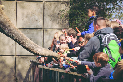 Happy people feeding elephant at zoo
