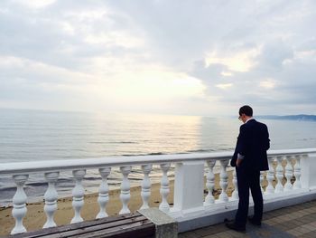 Full length of man standing on railing against sea
