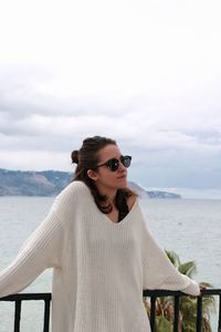 Young woman standing at beach against sky