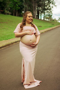 Full length of a smiling young woman standing on road