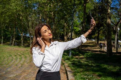 Portrait of young woman with arms raised standing on field